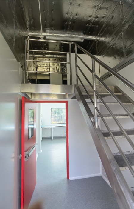 Containerized pharma cleanroom service mezzanine separating maintenance route from clean area